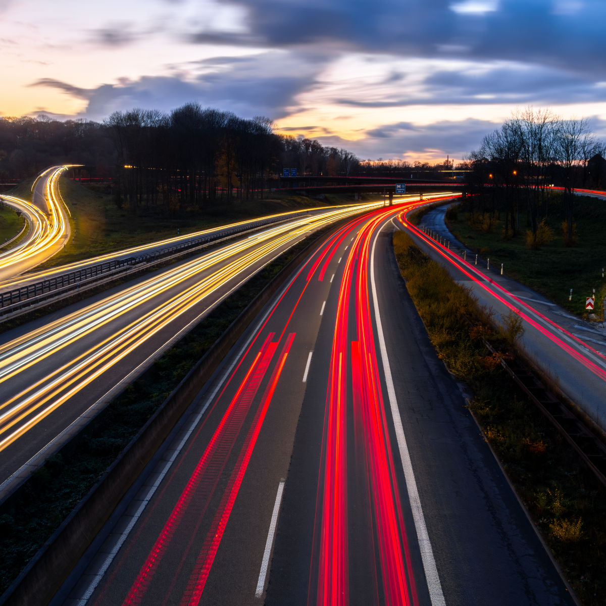 Autobahn crossing (A40 and A3) in Ruhr Basin Germany near Duisburg, Essen and Düsseldorf. Panoramic longtime exposure with red and white lights of passing cars at blue hour twilight after sunset.