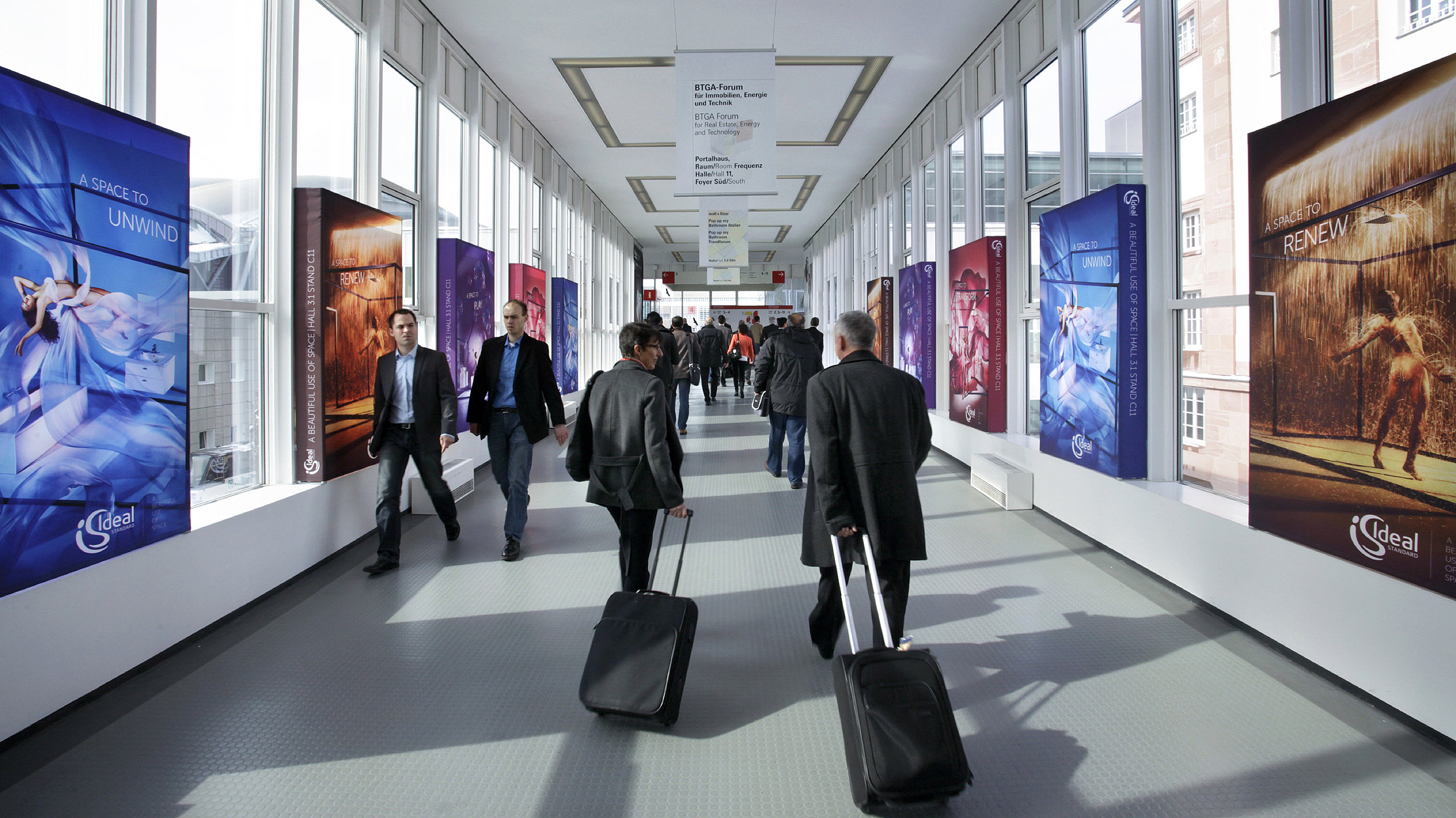 Messebesucher laufen in der Via Mobile an Werbedisplays vorbei